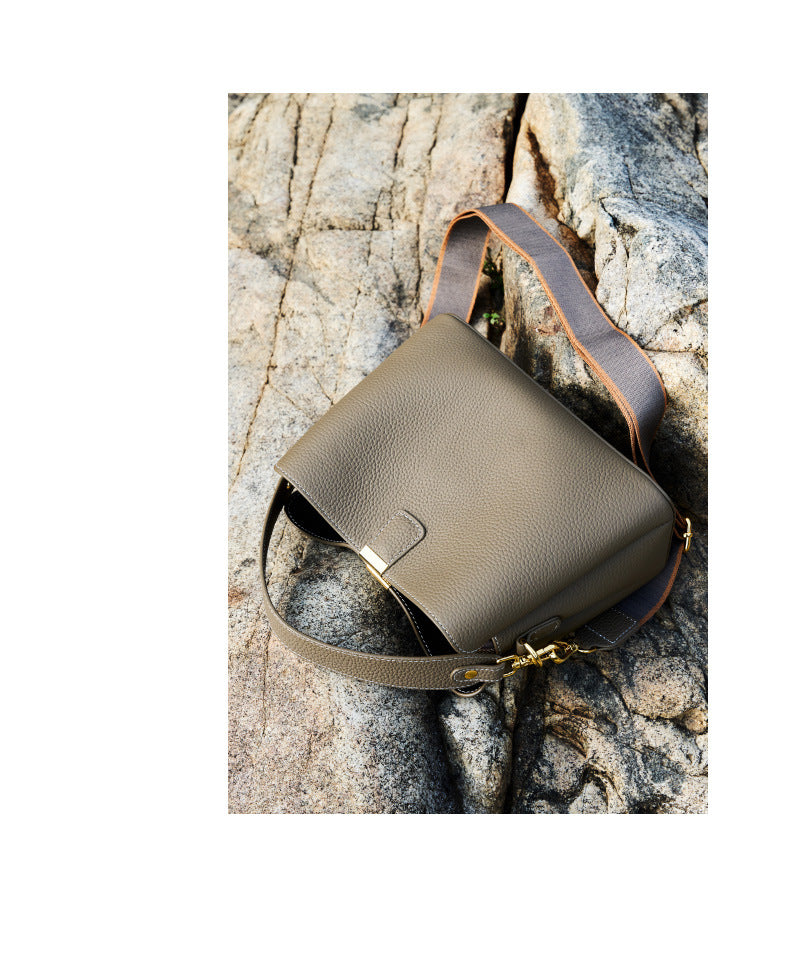 Brown leather bag resting on a rocky outdoor surface