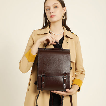 Model holding brown buckle flap backpack by top handle