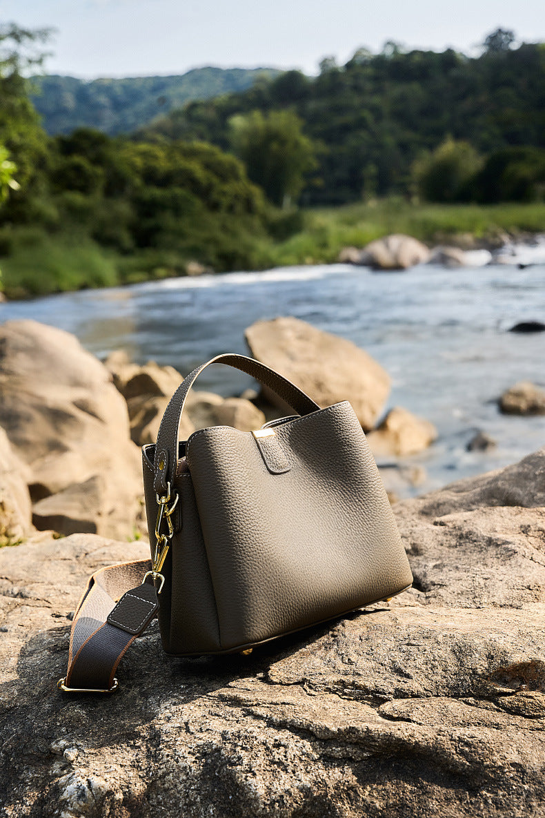 Brown leather bag placed on a rock by a river
