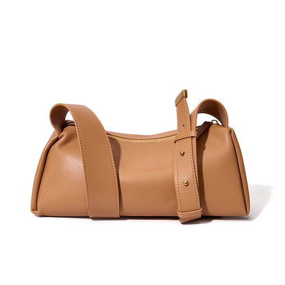 Apricot cowhide pillow crossbody bag with wide adjustable strap on white background