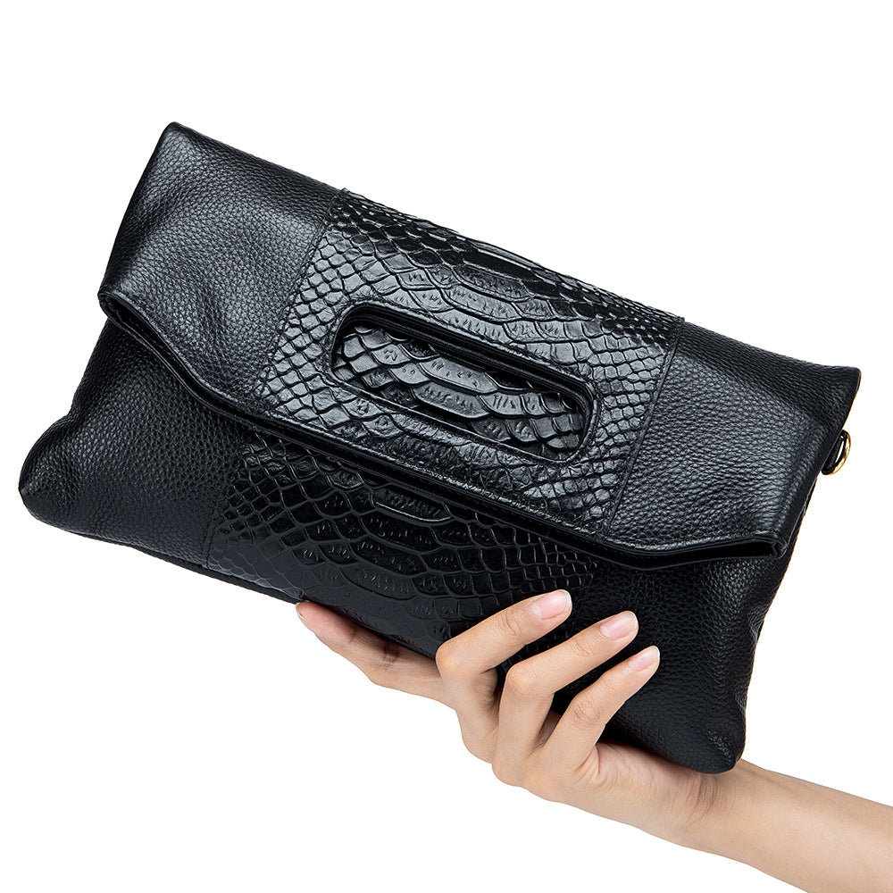 Black leather clutch shown in hand to illustrate its shape