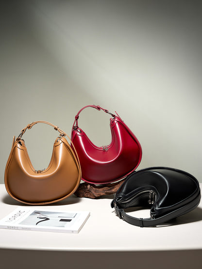 Three leather crescent bags in brown, burgundy and black