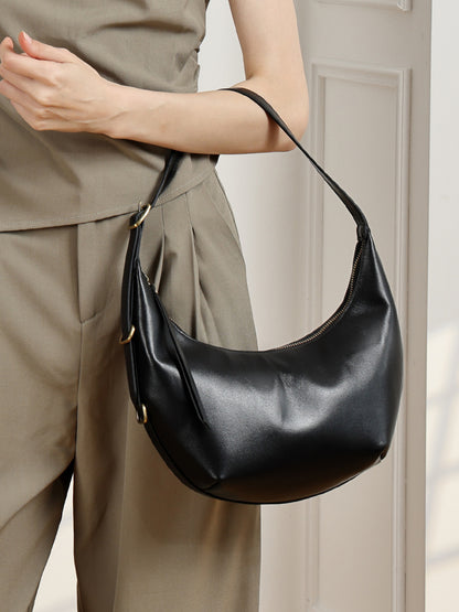 Black crescent bag held by model in neutral outfit