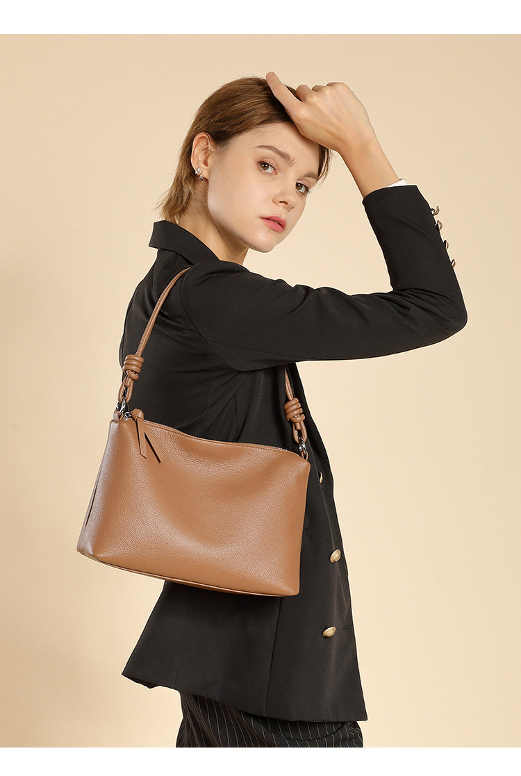 Model in black blazer carrying caramel leather pillow tote over her shoulder