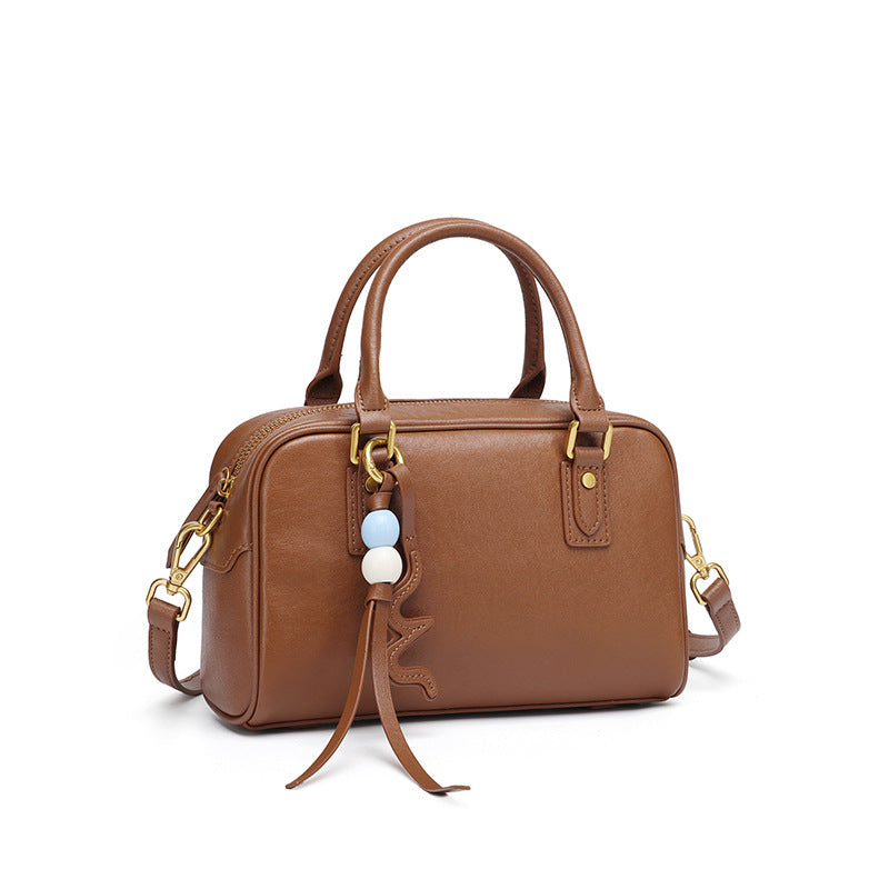 Caramel brown cowhide leather pillow bag with double top handles on a white background