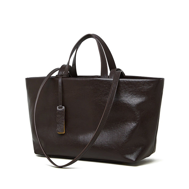 Coffee brown cowhide leather tote bag with crossbody strap on white background