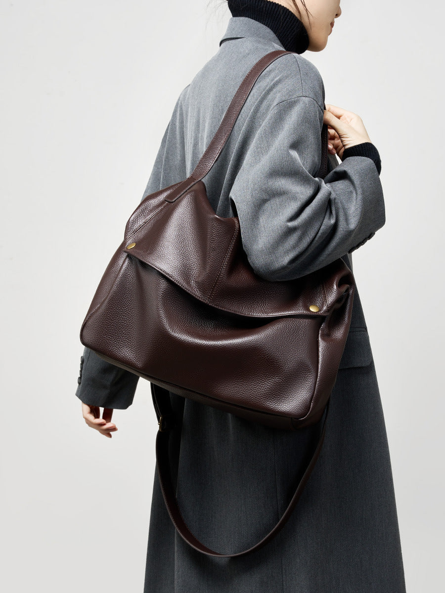 Coffee brown cowhide leather tote bag worn over the shoulder in a winter outfit