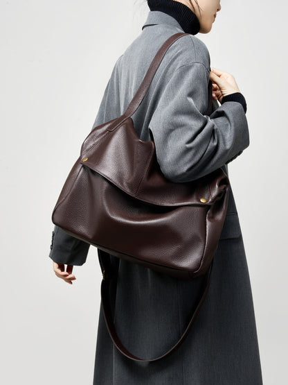 Coffee brown cowhide leather tote bag worn over the shoulder in a winter outfit