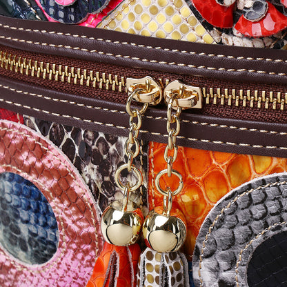 Close-up of decorative zipper pulls and mixed-pattern cowhide panels