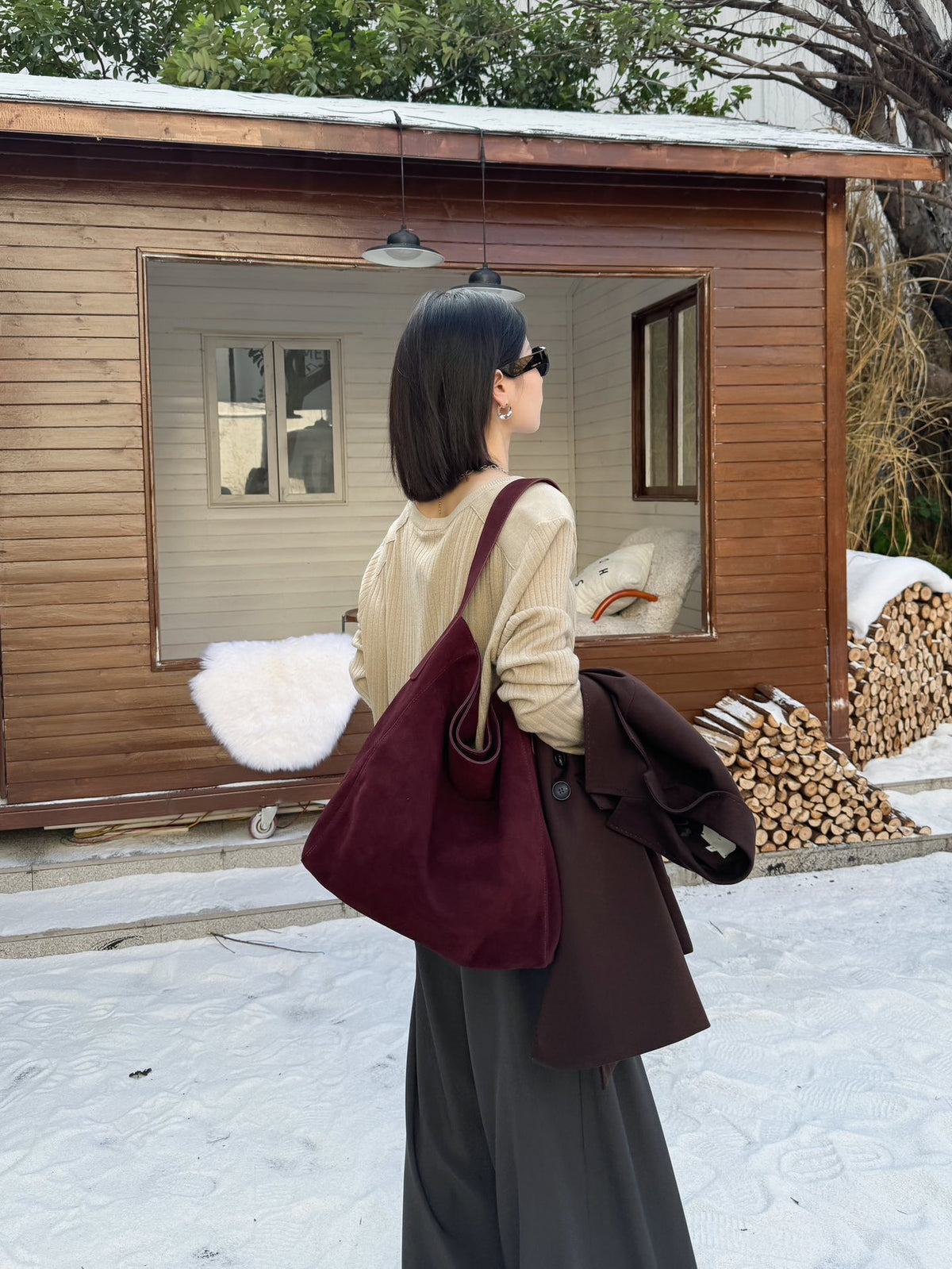 Side view of a model carrying the burgundy shoulder tote