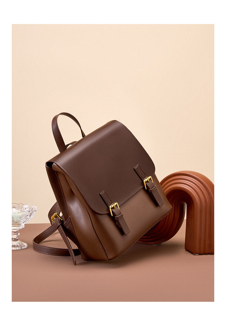 Dark brown leather backpack shown from a side angle on a terracotta surface with decorative objects