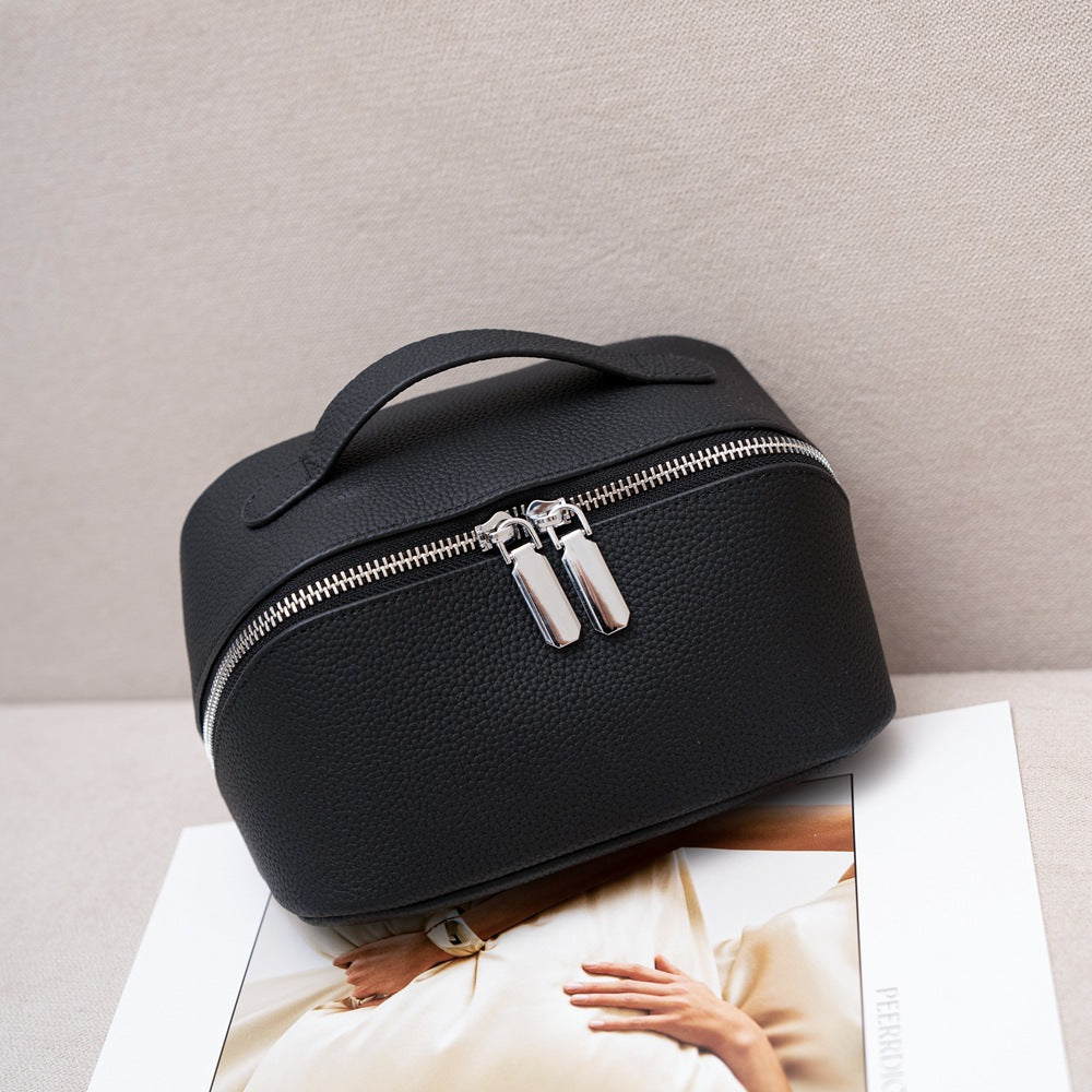 Black pebbled cowhide cosmetic pouch with top handle and twin zipper pulls