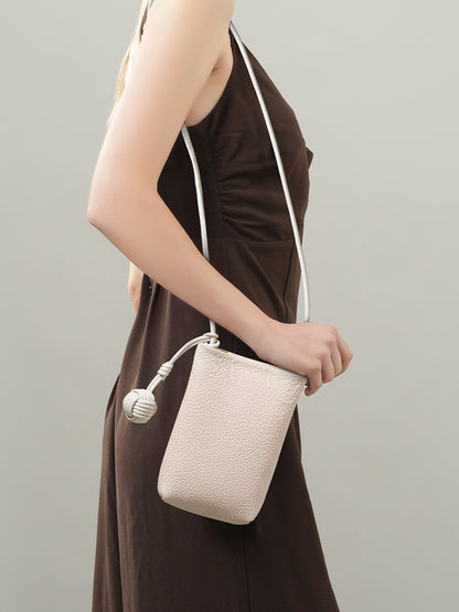 Milkshake white pebbled leather mini bucket phone bag worn crossbody with a brown slip dress