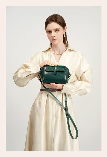 Model holding a deep green crossbody bag with contrast stitching