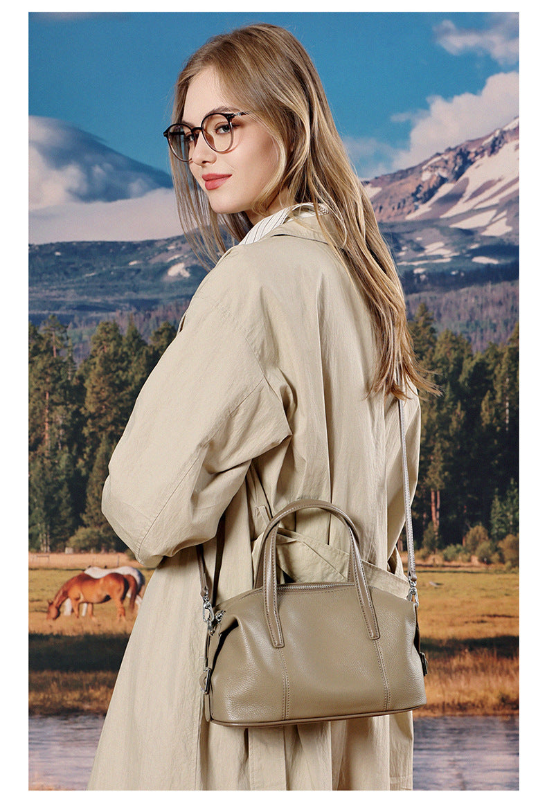 Model in beige outfit carrying elephant gray bag outdoors
