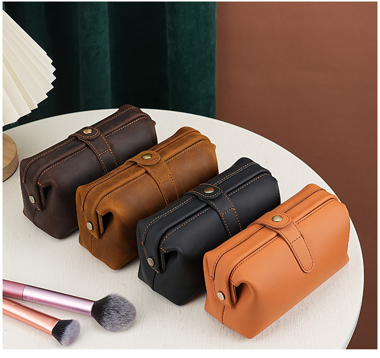 Cosmetic pouches in brown, black, and orange leather finishes arranged on a table