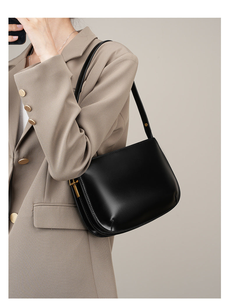 Model wearing a beige blazer carrying the black leather underarm bag on the shoulder