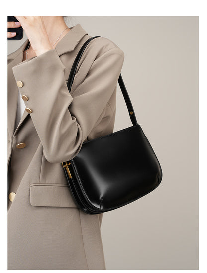 Model wearing a beige blazer carrying the black leather underarm bag on the shoulder