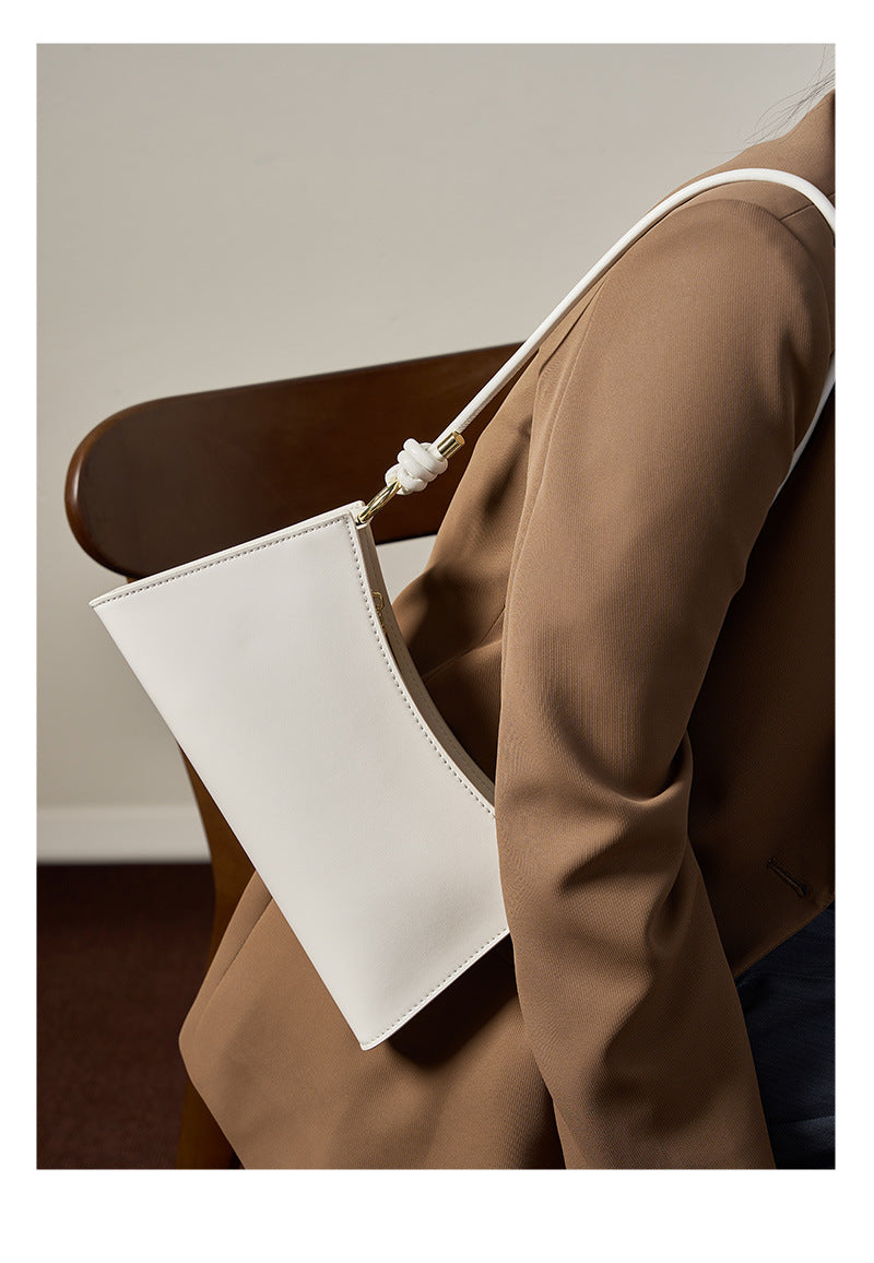 Cream white leather shoulder bag styled from a back angle with a brown blazer