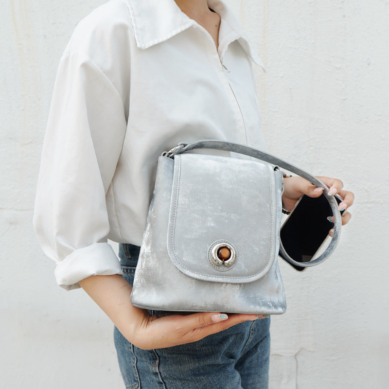 Silver gray split leather bucket bag held in hand with phone