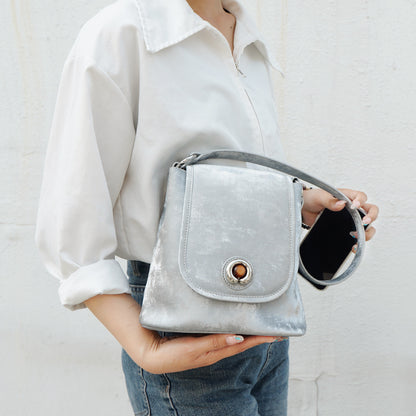 Silver gray split leather bucket bag held in hand with phone