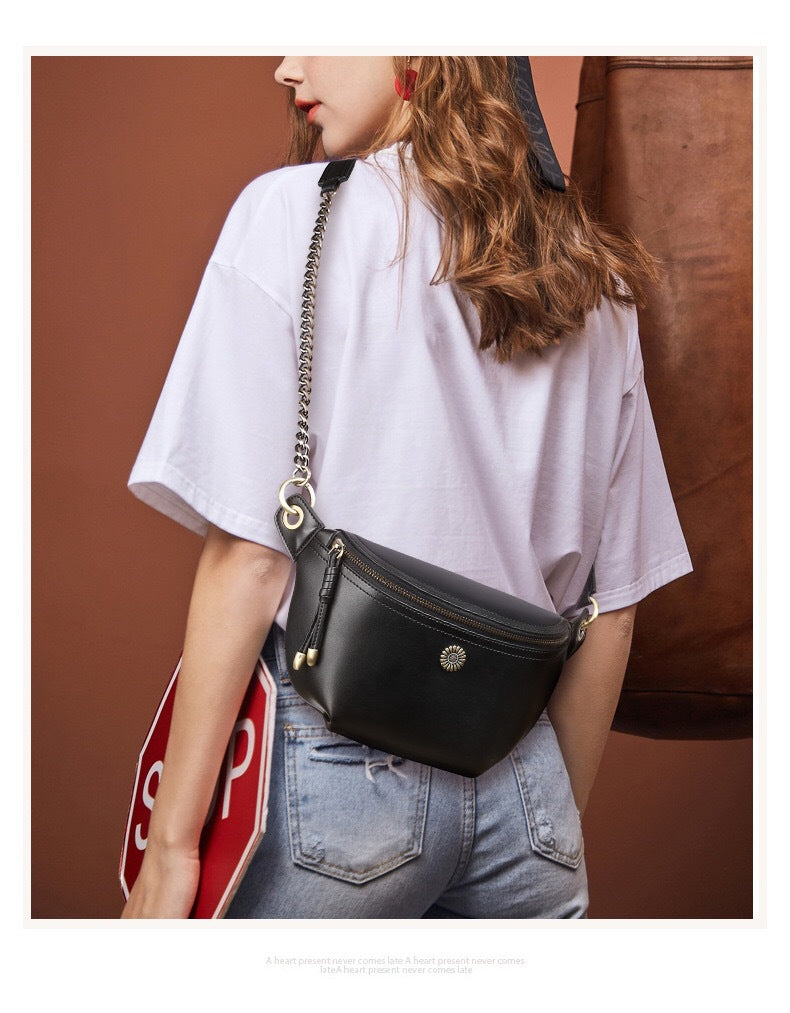 Black chain-strap belt bag worn crossbody with a white shirt and jeans