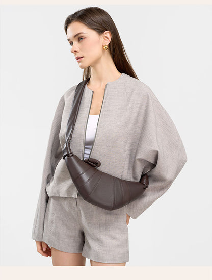 Model in gray linen set carrying coffee crescent bag crossbody