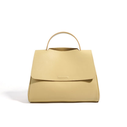 Yellow cowhide leather top-handle bag with flap closure on white background