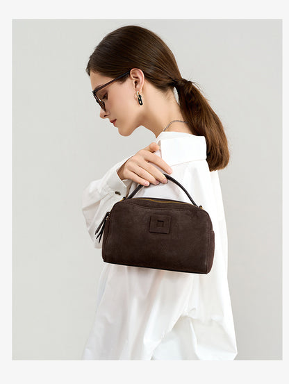 Model holding the nubuck cowhide bag by its top handle