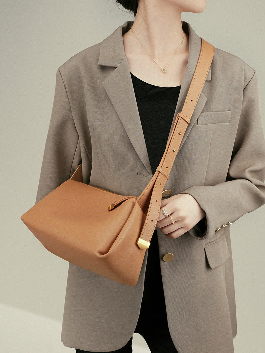 Apricot pillow crossbody bag worn crossbody with a beige blazer