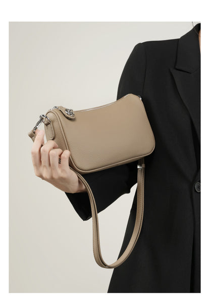 Side angle showing adjustable strap and turn-lock on taupe bag