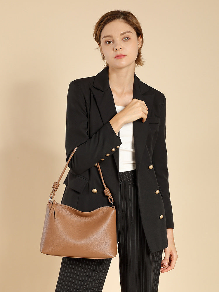 Model in blazer wearing caramel pebbled leather tote on her shoulder