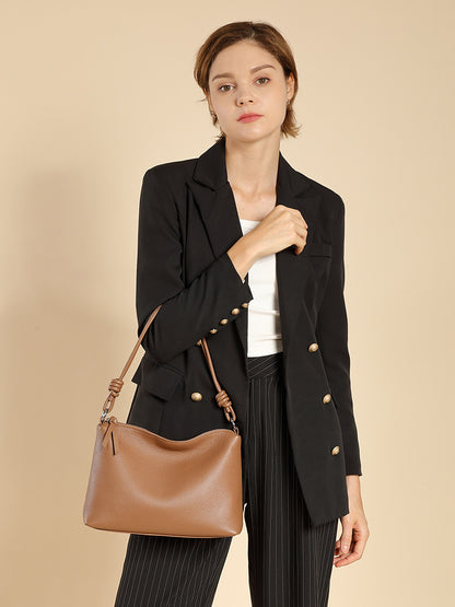 Model in blazer wearing caramel pebbled leather tote on her shoulder