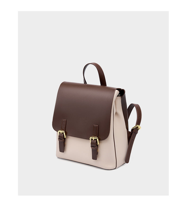 Three-quarter view of the two-tone backpack highlighting the flap, buckles, and top handle