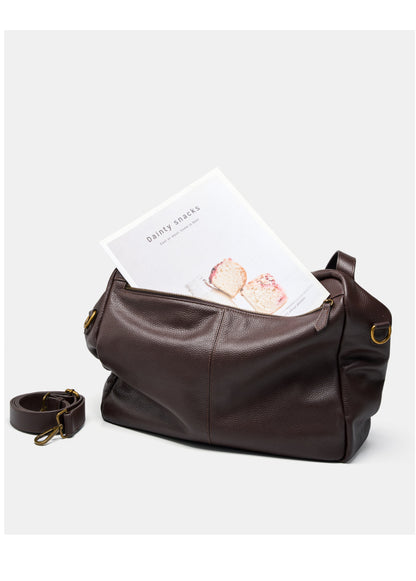Brown leather tote bag with a magazine tucked into the back zip pocket