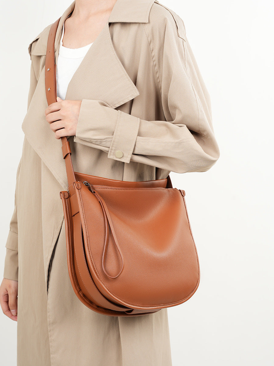 Tan leather hobo bag carried crossbody by model in beige trench
