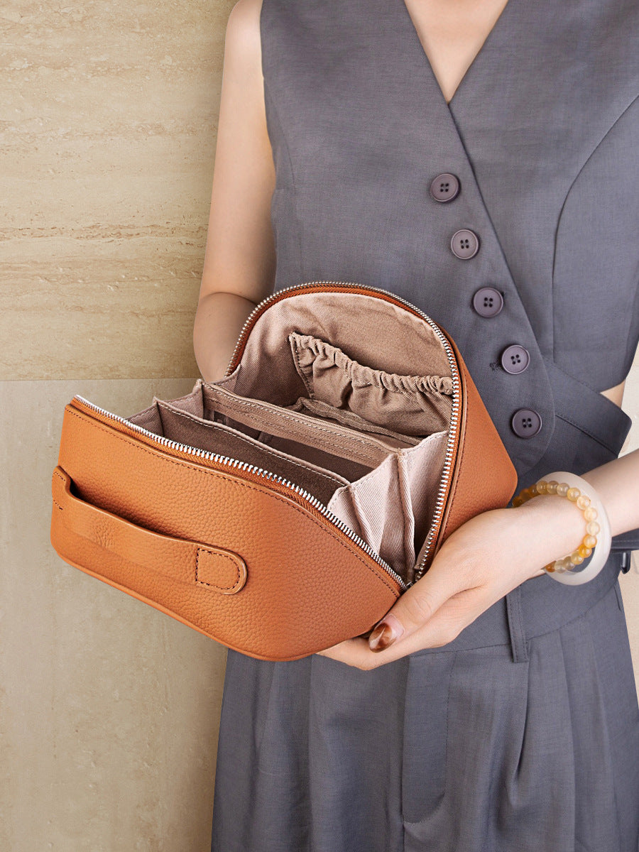 Open view of brown leather cosmetic pouch showing organized interior compartments and elasticated pocket