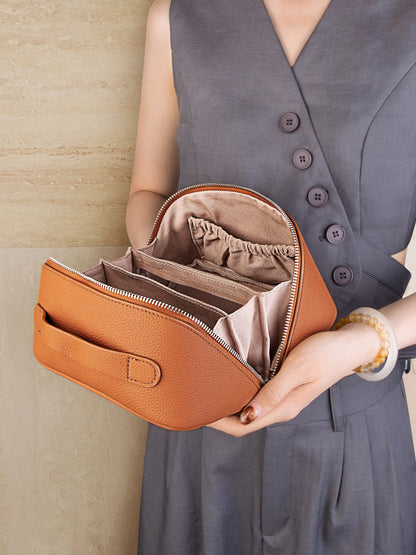 Open view of brown leather cosmetic pouch showing organized interior compartments and elasticated pocket