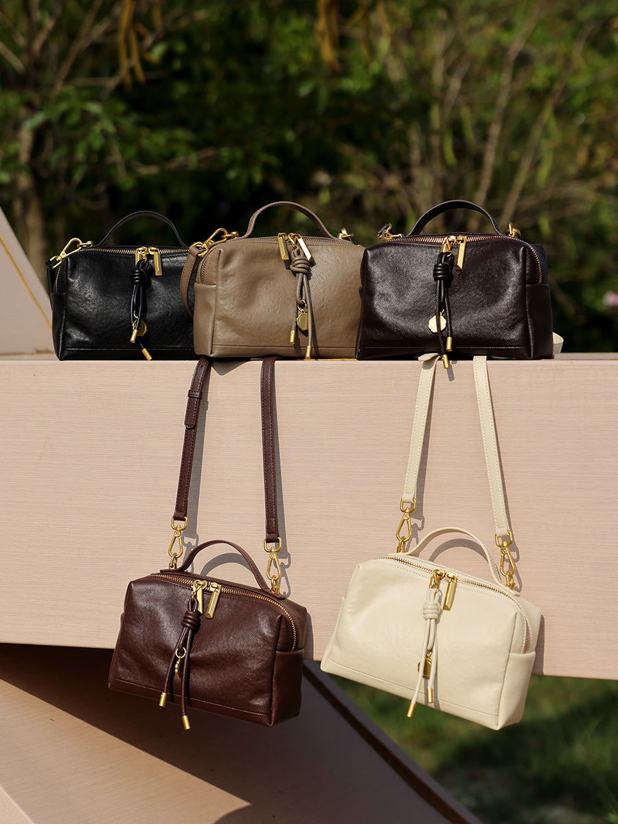 Five color lineup of cowhide leather crossbody bags in black, gray, coffee, brown, and off-white