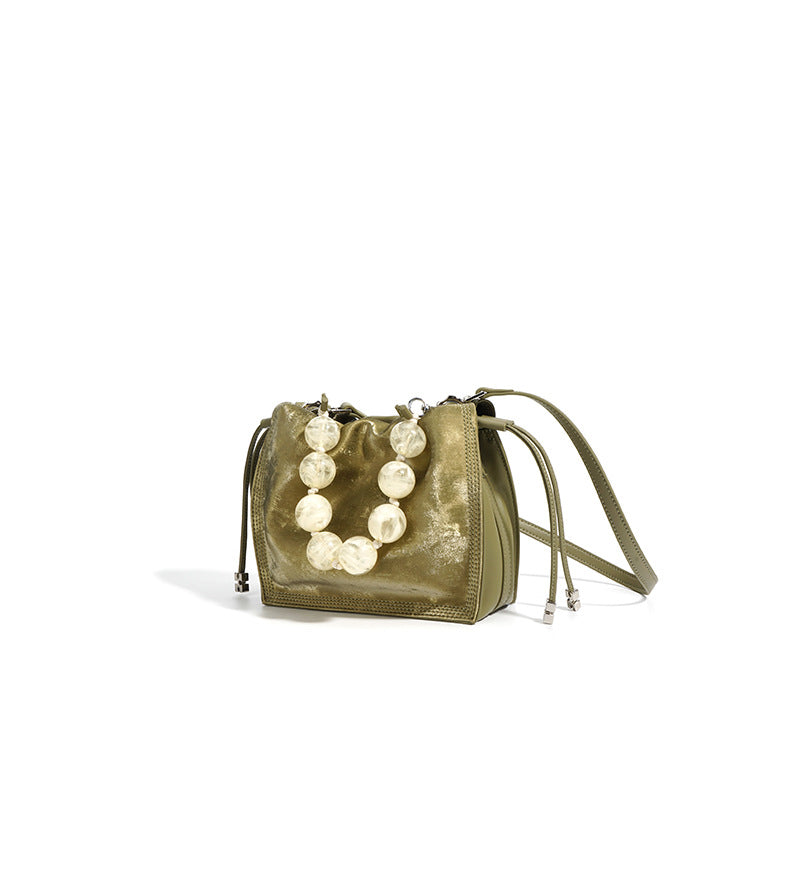 Champagne mini bucket bag styled at a three-quarter angle on white