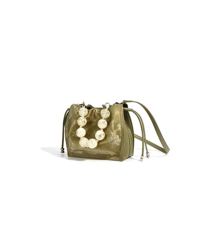 Champagne mini bucket bag styled at a three-quarter angle on white