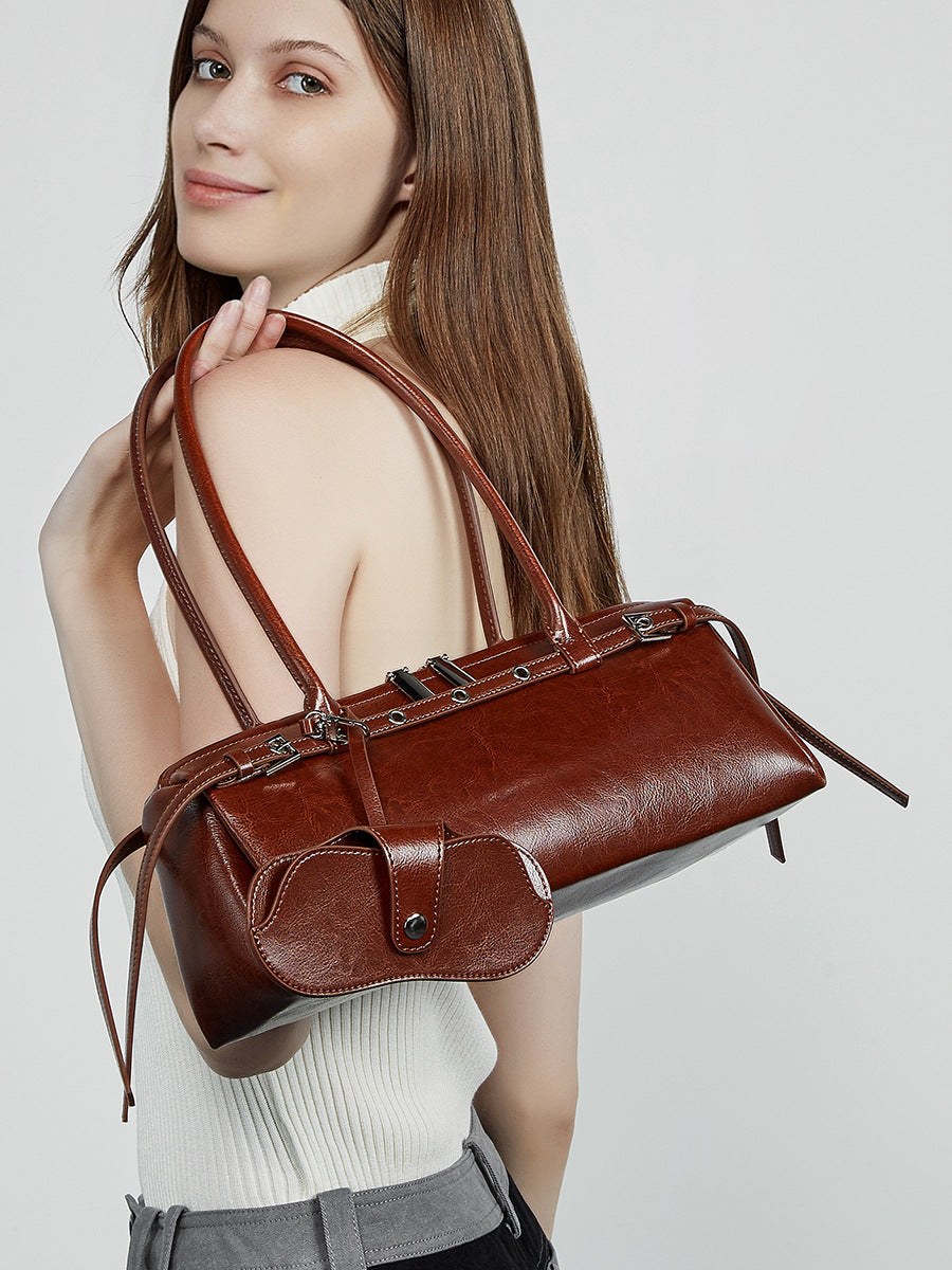 Back view of model holding brown barrel bag against white top