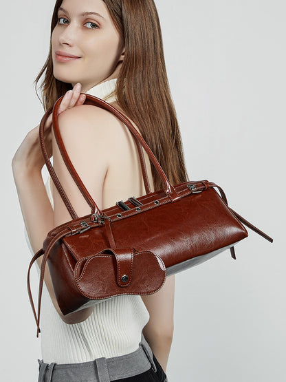 Back view of model holding brown barrel bag against white top