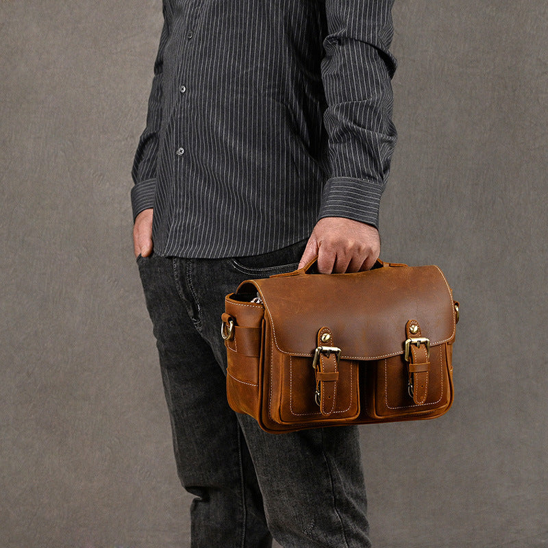 Brown leather camera bag held by its top handle