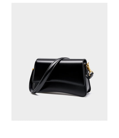 Front detail of black leather shoulder bag with curved flap and polished hardware
