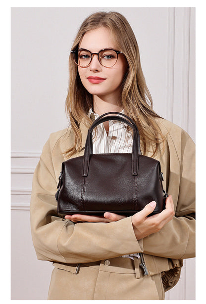 Model holding dark brown bag with both hands indoors