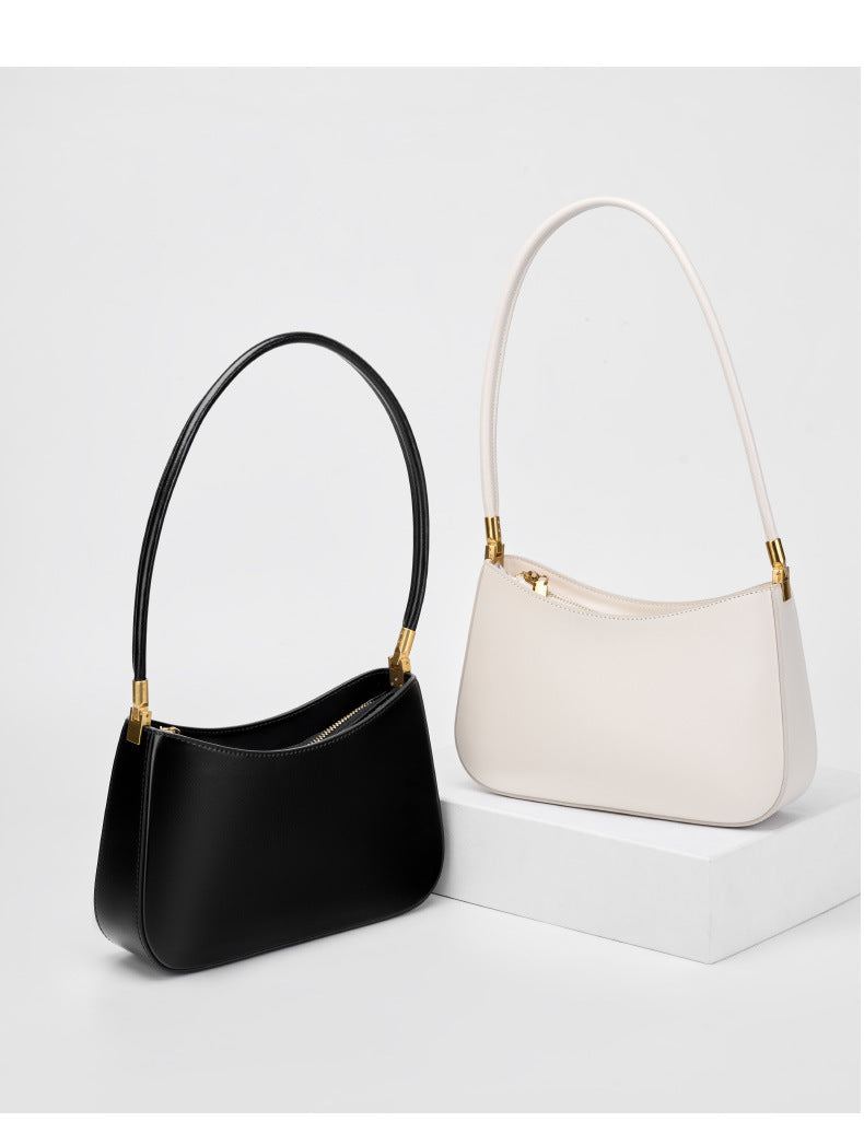Black and cream shoulder bags displayed side by side on a white pedestal
