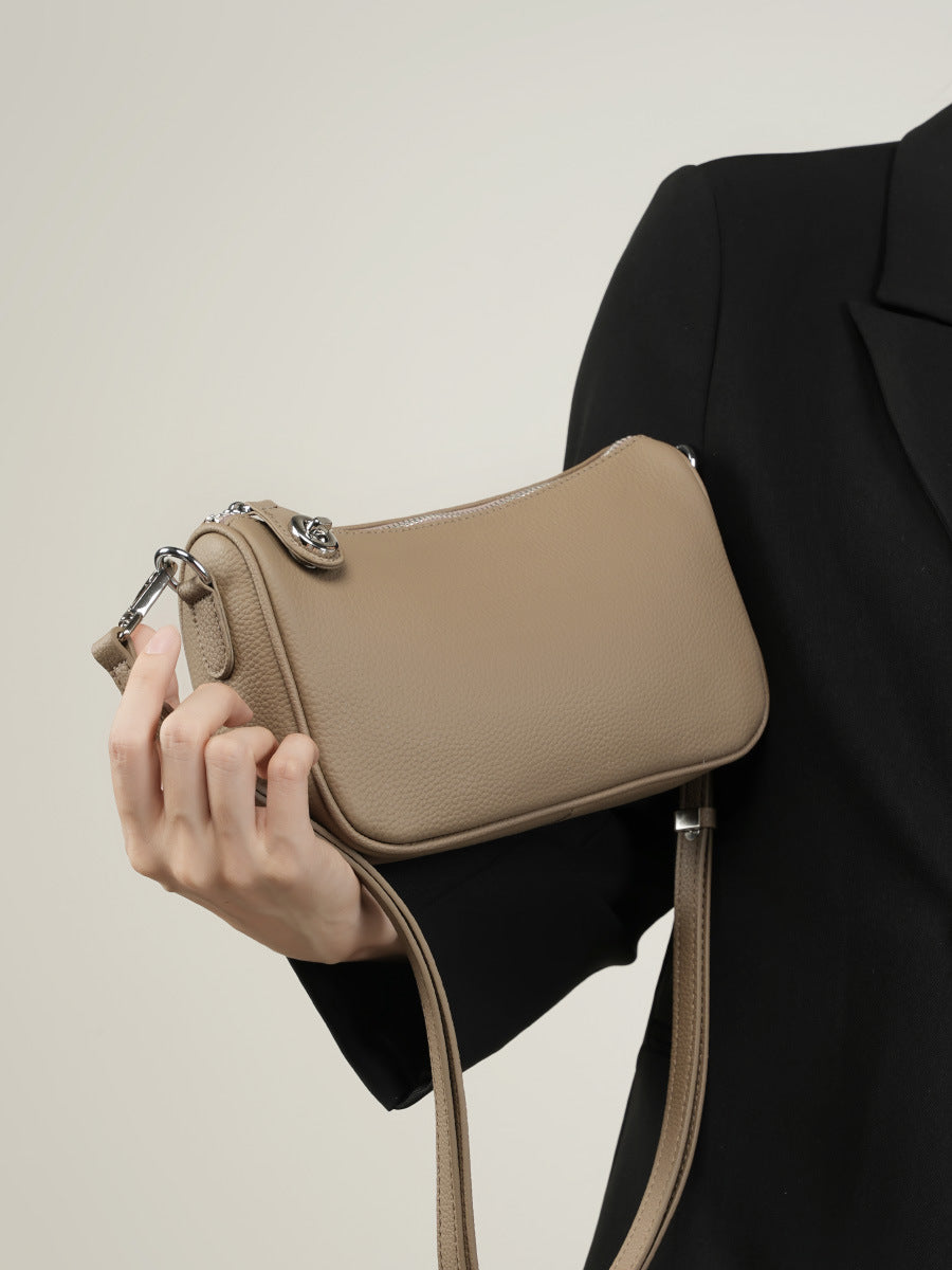 Detail of silver turn-lock zipper and strap attachment on taupe bag