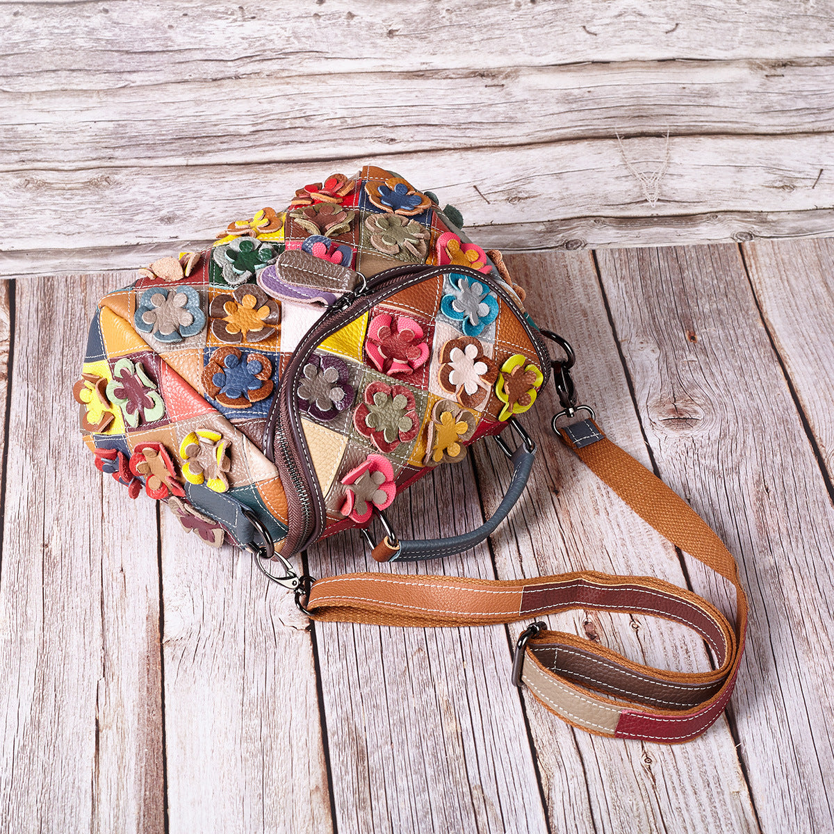 Overhead detail of floral appliques, zipper, handle, and shoulder strap