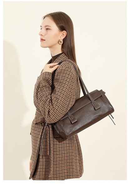 Model in houndstooth coat carrying dark brown cowhide leather shoulder bag on shoulder